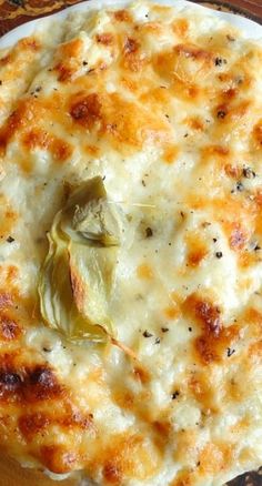 a white plate topped with cheesy food on top of a wooden cutting board