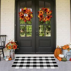 two black double doors with pumpkins and flowers on the front porch for fall decorations