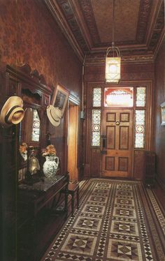 the hallway is decorated in wood and has an ornate tile floor, with two vases on either side of the door