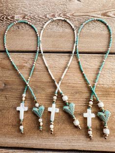 three necklaces with cross charms and beads on top of a wooden table next to each other