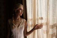 a woman standing in front of a curtain with her hand out to the side,