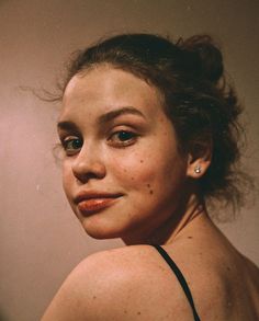 a woman with freckles on her face looking at the camera while wearing a black tank top