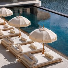 lounge chairs and umbrellas are lined up by the pool