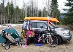 a woman sitting in front of a van with her bike and tent