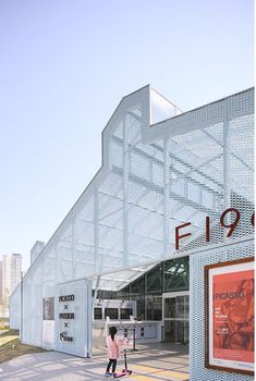 a person walking in front of a building with an advertisement on the side and a sign that says fi 99