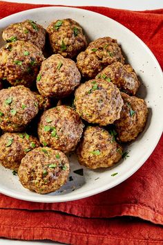 a white bowl filled with meatballs on top of a red towel