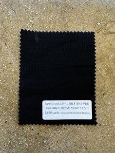 a black cloth with a white label on it sitting on the ground next to some sand