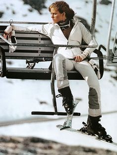 a woman sitting on top of a bench next to a ski lift in the snow