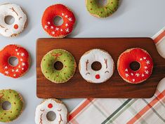 four decorated donuts are on a wooden board