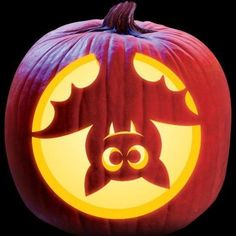 a carved pumpkin with an image of a bat on it's face in front of a black background