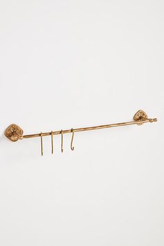 a pair of gold ear hooks hanging from a hook on a white wall with two pairs of earrings attached to it