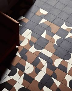 a black and white tiled floor with geometric shapes on the tile, as well as an orange chair