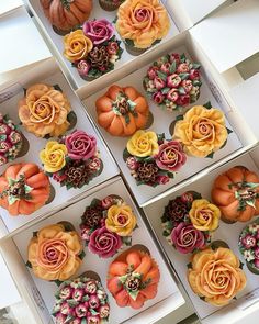 several decorated cupcakes in boxes with flowers and pumpkins on the top one