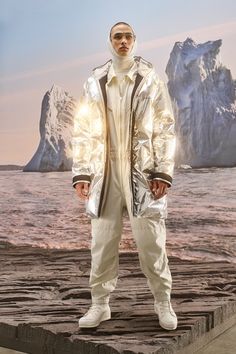 a man standing on top of a cement slab near the ocean wearing an all white outfit