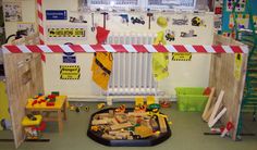 an indoor play area with wooden toys and construction signs on the wall, including ladders