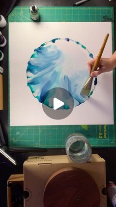 a person is using a brush to paint on a piece of paper with watercolors