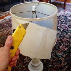 a person holding a yellow object in front of a lamp on a carpeted floor