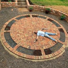 a man laying on top of a brick circle