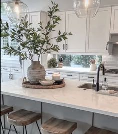 a kitchen island with stools and a potted plant on it in front of the sink