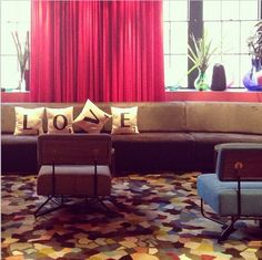 a living room filled with lots of furniture next to a red curtained window sill