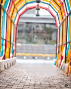 an archway with colorful ribbons hanging from it's sides and a light at the end