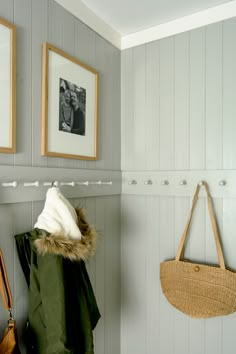 a coat rack with two coats hanging on it next to a handbag and purse