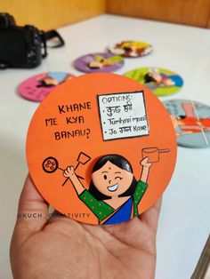 a hand holding an orange magnet with a cartoon character on it's front and back