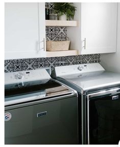 a washer and dryer sitting next to each other in a room with black and white wallpaper