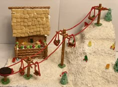 a cake made to look like a ski slope with a rope bridge and snow covered mountain in the background