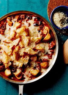 a pizza in a pan with cheese and toppings next to a wooden spatula