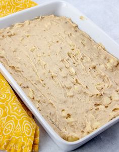 a pan filled with batter sitting on top of a yellow cloth next to a napkin