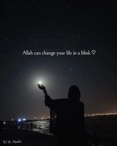 a person holding their hand up in the air at night with an islamic quote above it