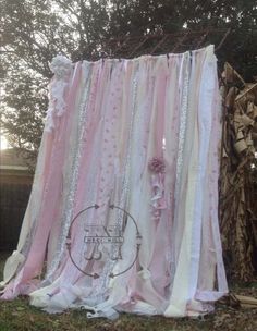 a pink and white curtain with sequins hanging from it's side in front of some trees