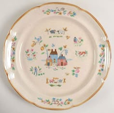 a white plate with an image of houses and animals painted on the side, sitting on a table