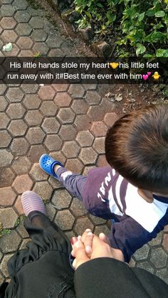 a little boy sitting on his father's lap looking down at the ground while he holds hands with him