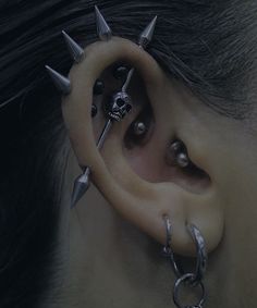 a person with some piercings on their ear and behind the ear is a pair of scissors