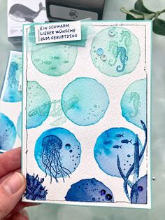 a hand holding up a card with blue watercolors and sea animals on it