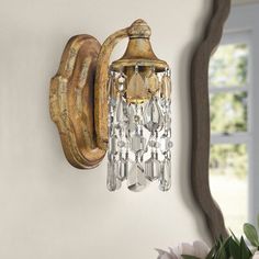 a wall light that is hanging from the side of a wall next to a vase with flowers