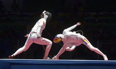 two men performing acrobatic tricks on the balance beam