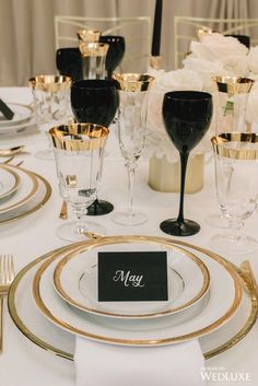 the table is set with black and gold place settings