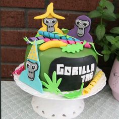 a birthday cake decorated with cartoon characters and decorations on a table next to a potted plant