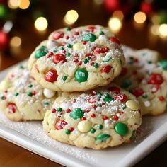 three cookies with m and m on them are sitting on a white plate next to christmas lights