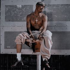 a man sitting on top of a fire hydrant in front of a metal wall