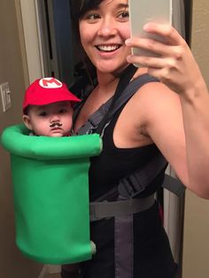 a woman taking a selfie with her child in a costume that looks like mario