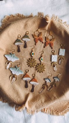 an assortment of earrings laid out on a piece of cloth with tassels around them