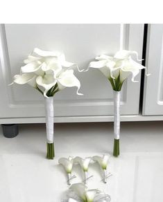 three white flowers in vases sitting on a counter