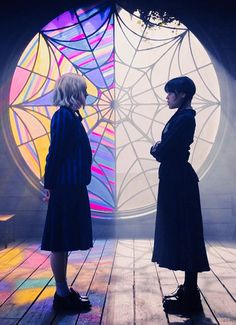 two people standing on a wooden floor in front of a stained glass window with spider webs