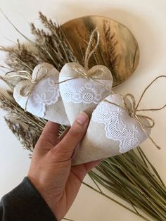 two heart shaped sacs tied with twine and placed next to dried plants on a white surface