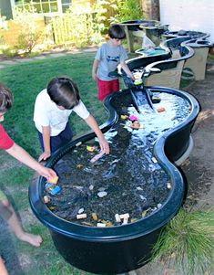 two boys are playing with garbage in an outdoor water feature that looks like a guitar