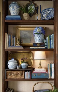 a bookshelf filled with lots of books and vases on top of it